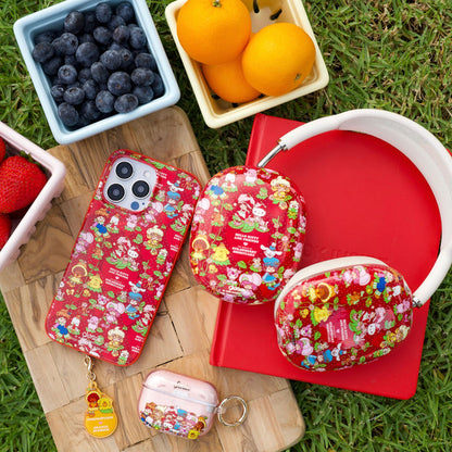 Hello Kitty & Friends x Strawberry Shortcake red iPhone cases, matching AirPods case and headphones arranged on grass with bowls of fruit
