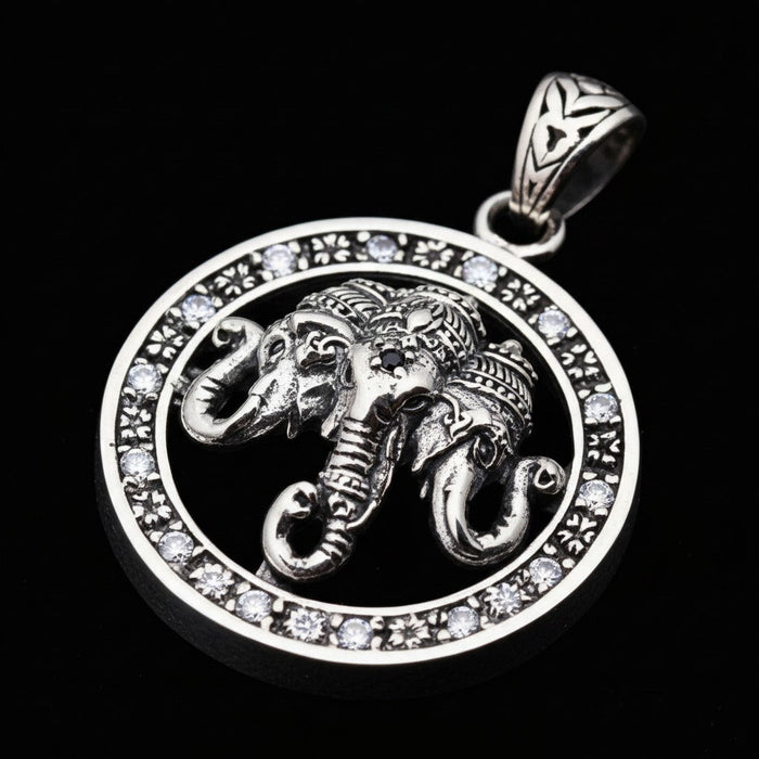 Solid silver Hindu elephant pendant with three heads and a black center stone, shown on a black background.