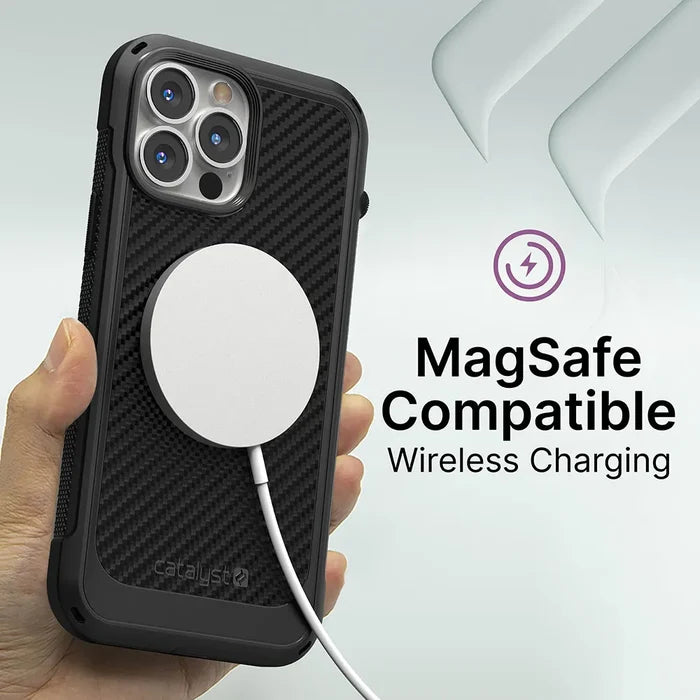 A hand holds an iPhone 13 Pro Max in the Catalyst Case US Vibe Case (MagSafe Compatible) with a wireless charger attached. The text says “MagSafe Compatible Wireless Charging” and there’s a purple wireless charging icon beside it.