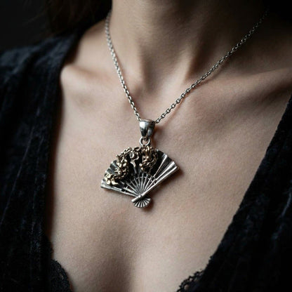 Woman wearing dragon fan gothic pendant on silver chain against black top, showing brass dragon and sterling silver fan scale on skin