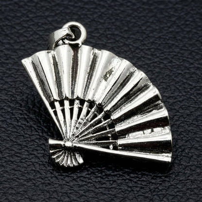 Sterling silver folding fan pendant with pleated ribs and jump ring bail on dark leather background