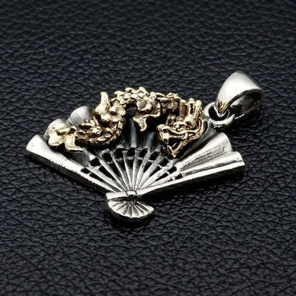 Three-quarter perspective of folding fan pendant showing sterling silver pleated ribs beneath coiling brass dragon motif