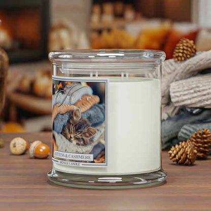 Kittens & Cashmere 4-wick Candle jar with a cat-themed label on a wooden surface with autumn decorations.