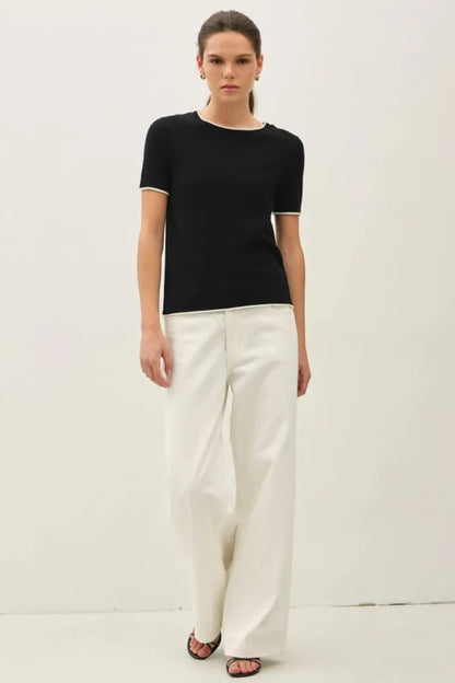 Black knit essential short sleeve sweater top with white trim along neckline and sleeve hems layered look essential short sleeve