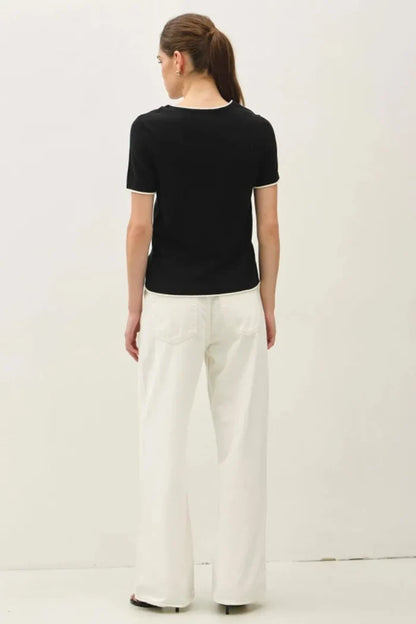 Black essential short sleeve sweater top with white trim on neckline and sleeve hems for layered look essential short sleeve