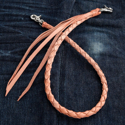 Close-up of handcrafted braided cowhide leather wallet chain with leather tassels and stainless steel clasp on denim background