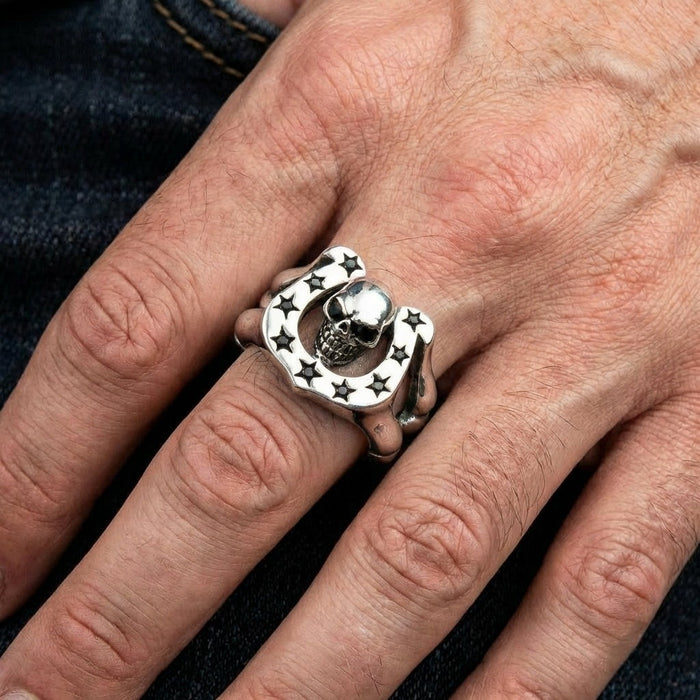 Man wearing skull horseshoe sterling silver ring on finger with denim background showing ring size and fit