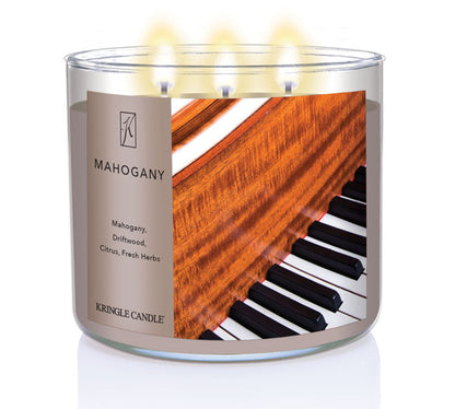 A three-wick lit candle in a clear glass jar with a luxurious wood and music-themed label. The candle’s wax is a rich brown, and all three wicks are burning.