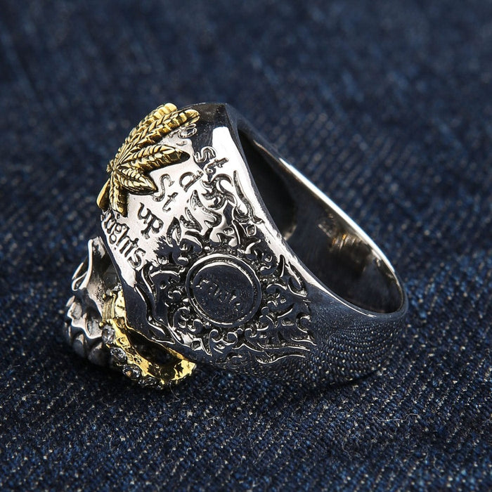 Profile view of 925 sterling silver skull ring featuring brass marijuana leaf crown