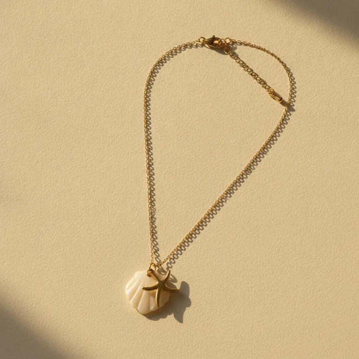 A delicate nautical gold plated necklace with a white gold plated seashell pendant and a starfish charm necklace