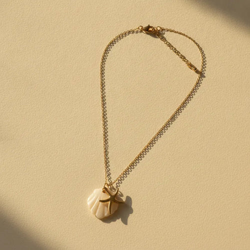 A delicate nautical gold plated necklace with a white gold plated seashell pendant and a starfish charm necklace