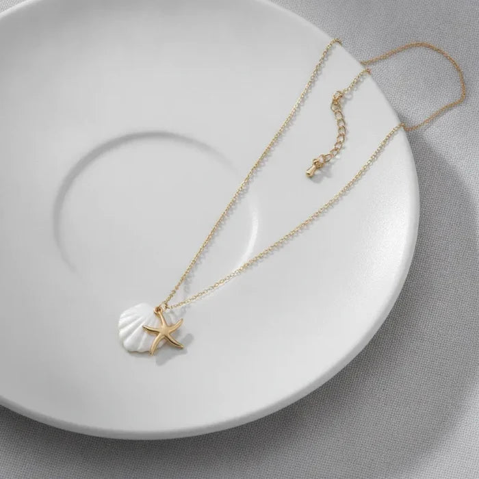 Navigational gold plated seashell and starfish charm necklace with a delicate gold chain and white shell pendant