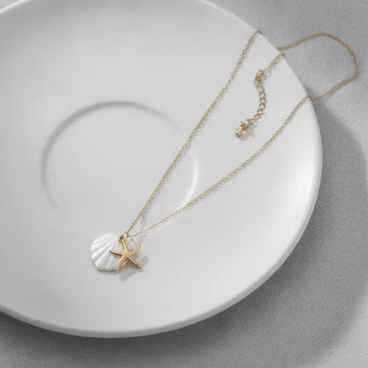 Navigational gold plated seashell and starfish charm necklace with a delicate gold chain and white shell pendant