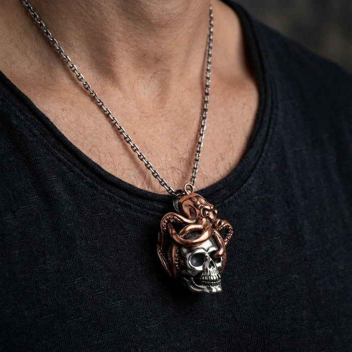 Octopus skull pendant necklace featuring silver skull wrapped with rose gold octopus tentacles on steel chain worn by male model in black shirt