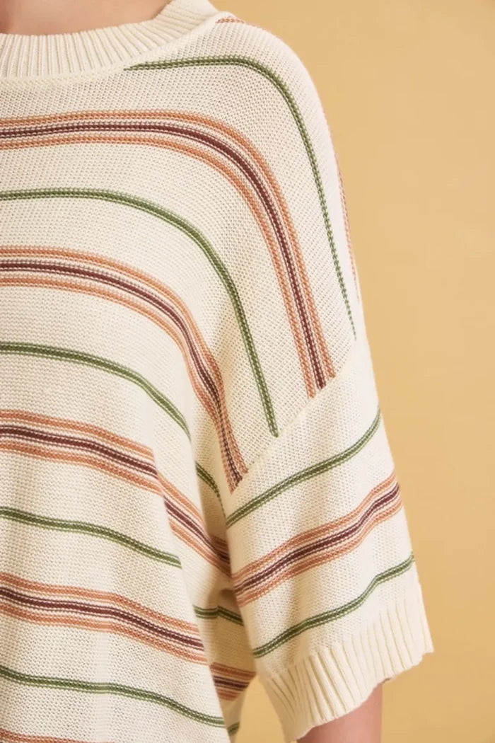 A cozy cream-colored oversized cut half sleeve sweater with soft terracotta and olive green knit stripes