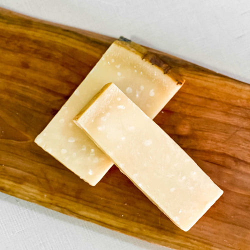 PARMIGIANO-REGGIANO cheese on wooden board with crumbly texture and nutty aroma.