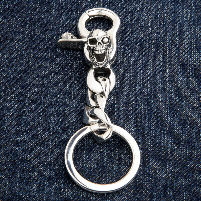 Full view of heavy silver skull keychain on denim background
