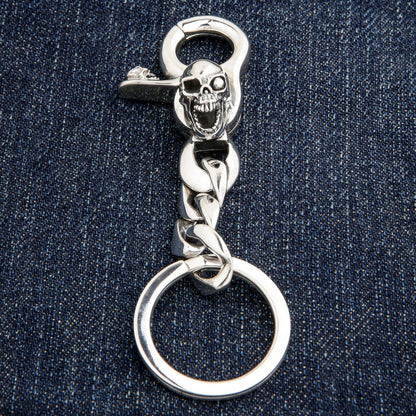 Full view of heavy silver skull keychain on denim background