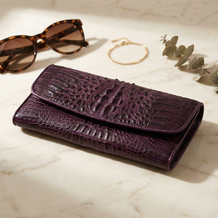 Lifestyle flat-lay of the purple crocodile women's wallet on marble with sunglasses and gold bracelet