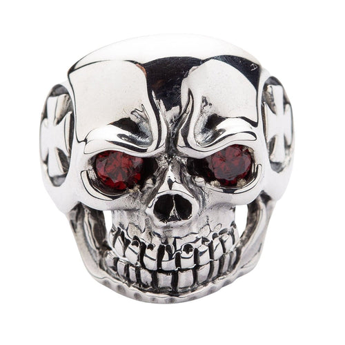 Direct front view of a grinning skull ring with red garnet-colored eyes, emphasizing the aggressive teeth and nose detail.