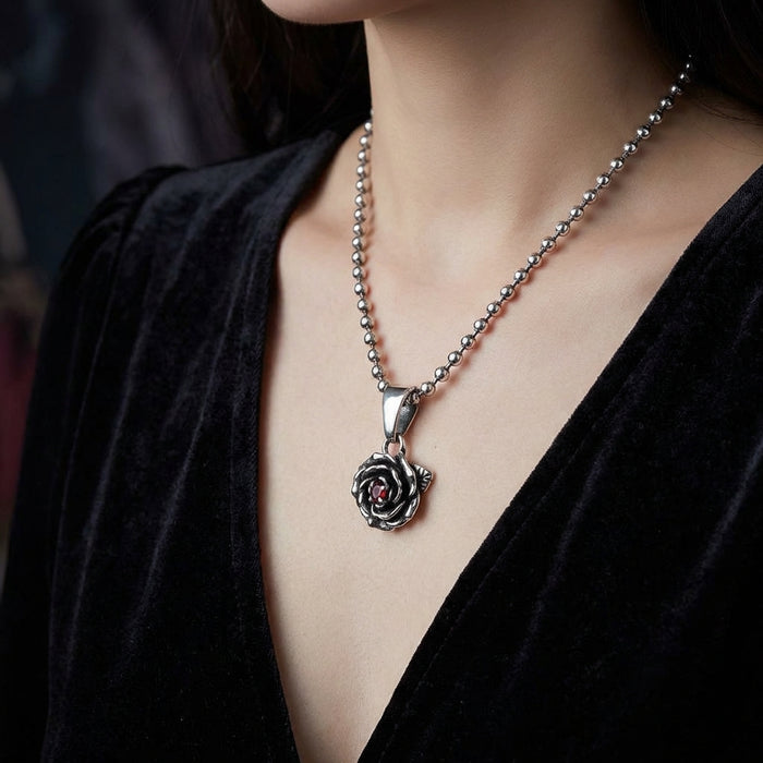 Silver rose pendant necklace with red gemstone center on ball chain worn by model in black velvet v-neck top, gothic romantic jewelry style