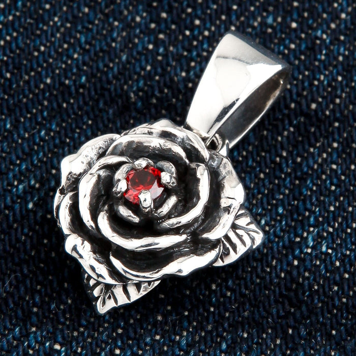 A unisex sterling silver rose pendant featuring a central red garnet and a dark, oxidized finish.