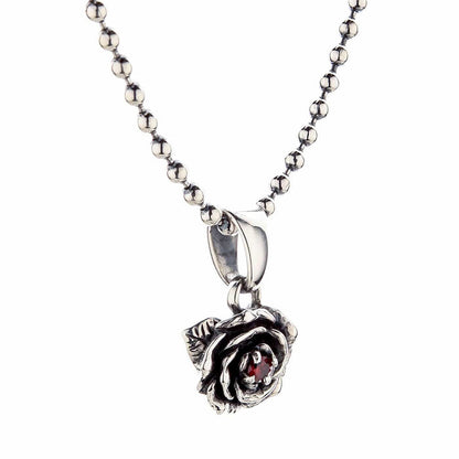 A detailed overhead view of the sterling silver floral pendant, designed as a rose with a fiery garnet gem.
