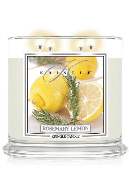 Lit Kringle Candle in Rosemary Lemon scent with glowing flames and label showing lemons and rosemary.