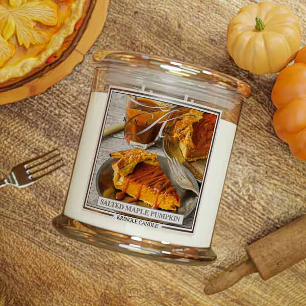 Kringle Candle salted maple pumpkin scented jar on a wooden surface with pumpkins and pie slices.