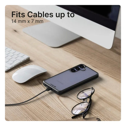 A Samsung Galaxy S24 in a Catalyst Case US Impact Protection Case is charging on a wooden desk near eyeglasses, a monitor, white keyboard, and mouse. Text at top left: "Fits Cables up to 14 mm x 7 mm.