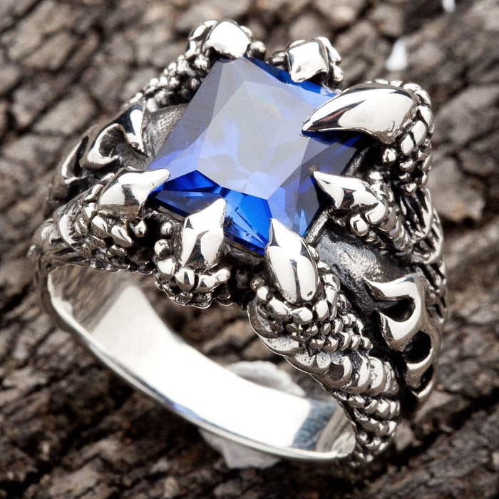 A men's solid sterling silver ring featuring four monstrous claws clutching a massive, square-cut blue sapphire CZ stone.