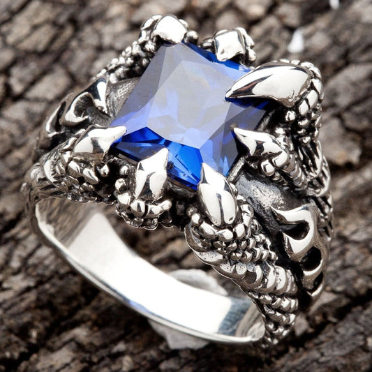 A men's solid sterling silver ring featuring four monstrous claws clutching a massive, square-cut blue sapphire CZ stone.
