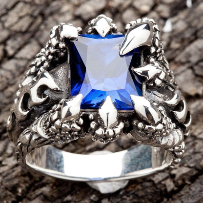 A gothic-style ring with monster talons holding a large blue sapphire, a piece of men's fantasy jewelry.