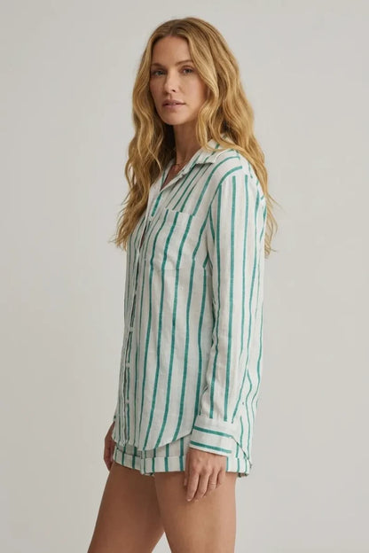 A woman wearing a white and green vertically striped long-sleeved saturdays stripe button down shirt with rolled cuffs