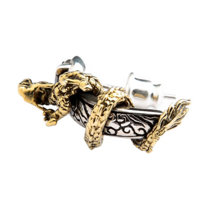 Two-tone stud from the side, a brass dragon coiled over engraved dark silver above the post and butterfly back.