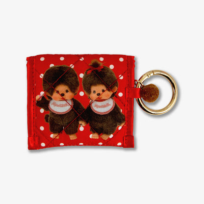 Close-up of Sonix x Monchhichi quilted AirPods pouch showing red polka-dot print and gold key ring on white background