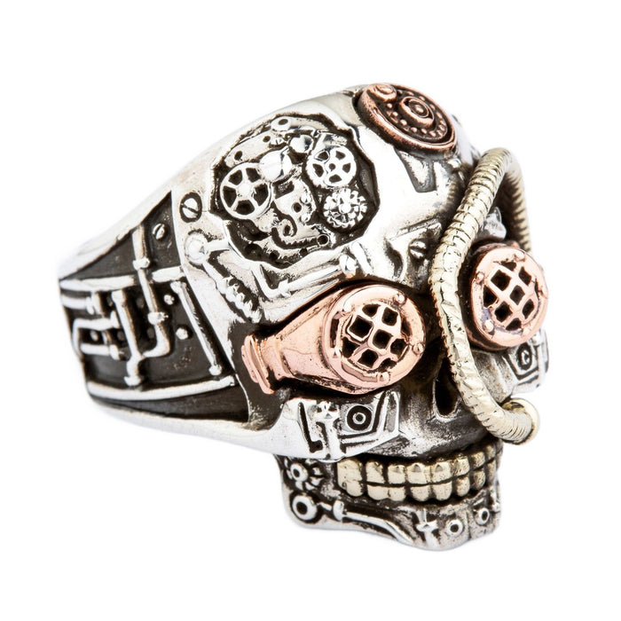 A sterling silver steampunk skull ring with copper goggles and brass gear details.