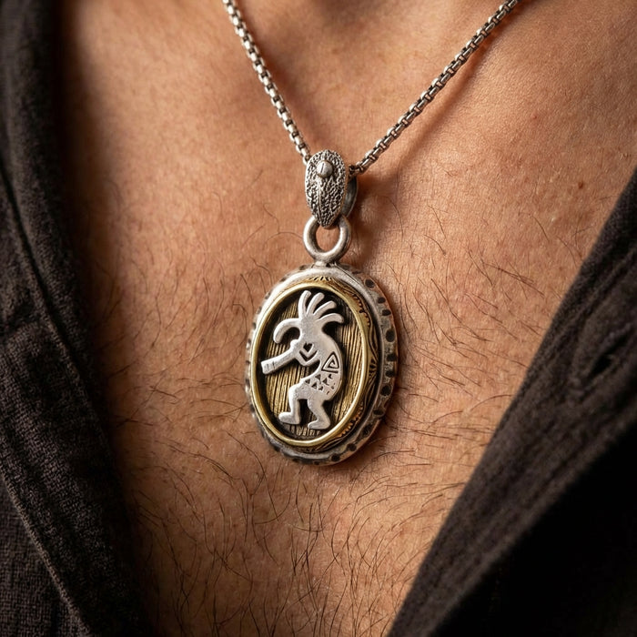 Silver and brass Native American Kokopelli necklace worn on a man's chest, featuring a dancing flute player figure on an oval medallion with textured border