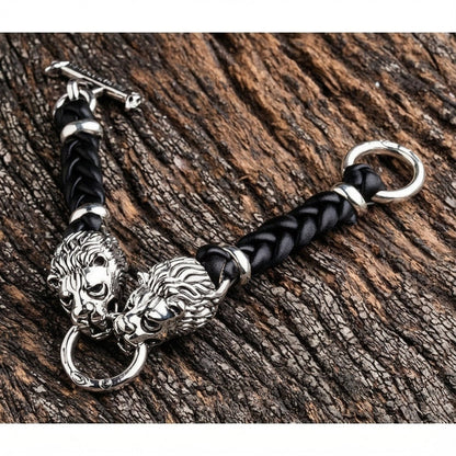 Sterling silver lion head bracelet with black braided leather and T-bar clasp on wood background