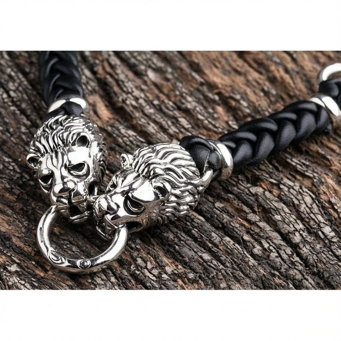 Close-up of two sterling silver lion heads with detailed manes gripping center ring on leather bracelet