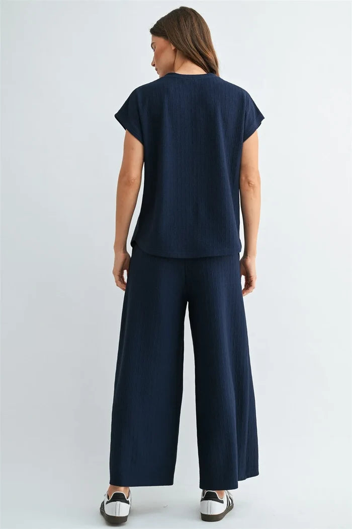 Navy blue textured knit two-piece set featuring a knit dolman short sleeve top and wide-leg pants