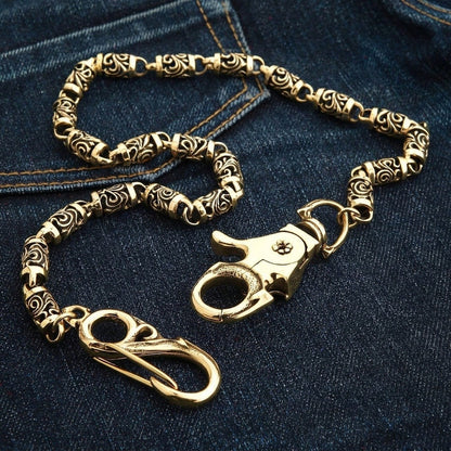 Reverse face of the brass lobster claw clasp with its small flower rivet and oval bail, resting on dark denim.