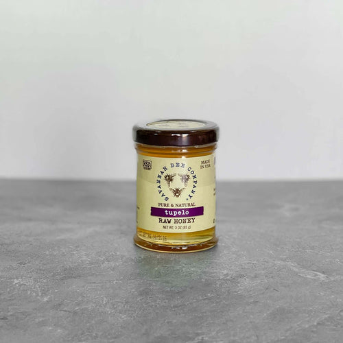 Savannah Bee Company Tupelo Honey jar, 3oz, on a gray surface.