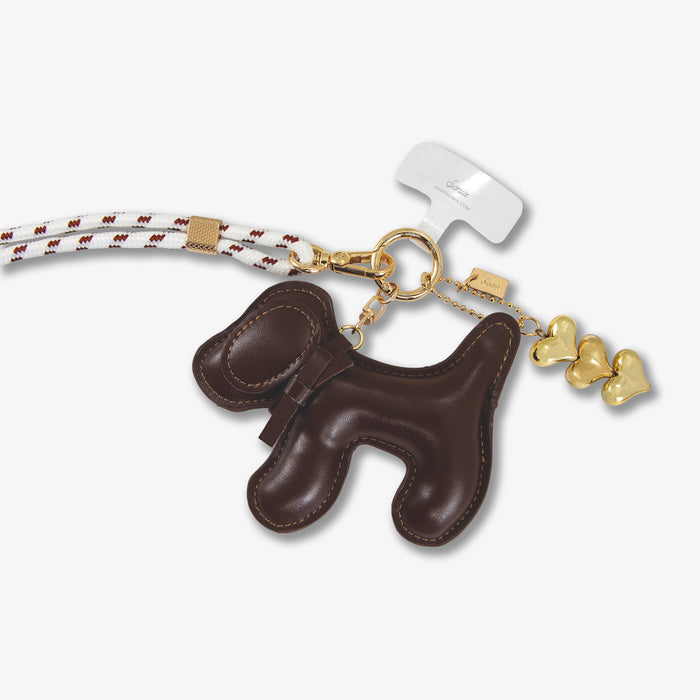 Close-up of Universal crossbody phone strap showing chocolate plush dog charm, braided white-and-brown rope strap and gold hardware on white background