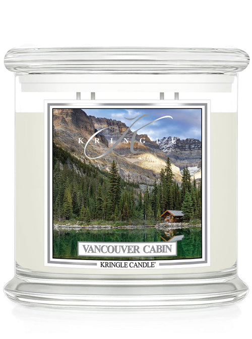 Unlit XL 4-Wick candle with a label showing a cabin by a forest and lake, under mountain peaks.