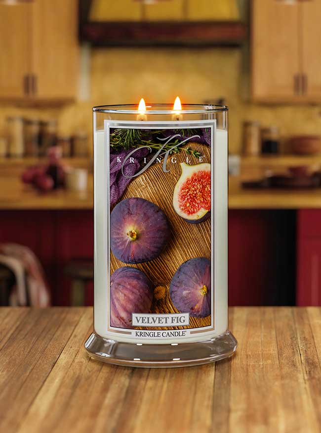 Lit Velvet Fig 2-wick candle. Label shows whole and half figs on wood with herbs.