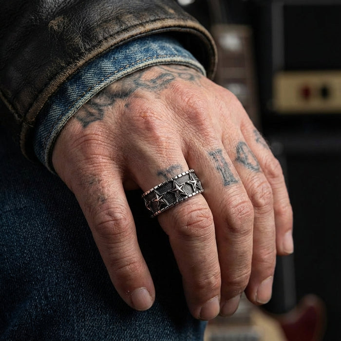 Vintage sterling silver star ring worn on tattooed male hand against black leather jacket and denim, showcasing detailed textured band design