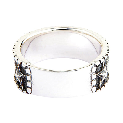 Polished sterling silver ring with a wide band, featuring dark, embossed star patterns on its sides, angled on a white background